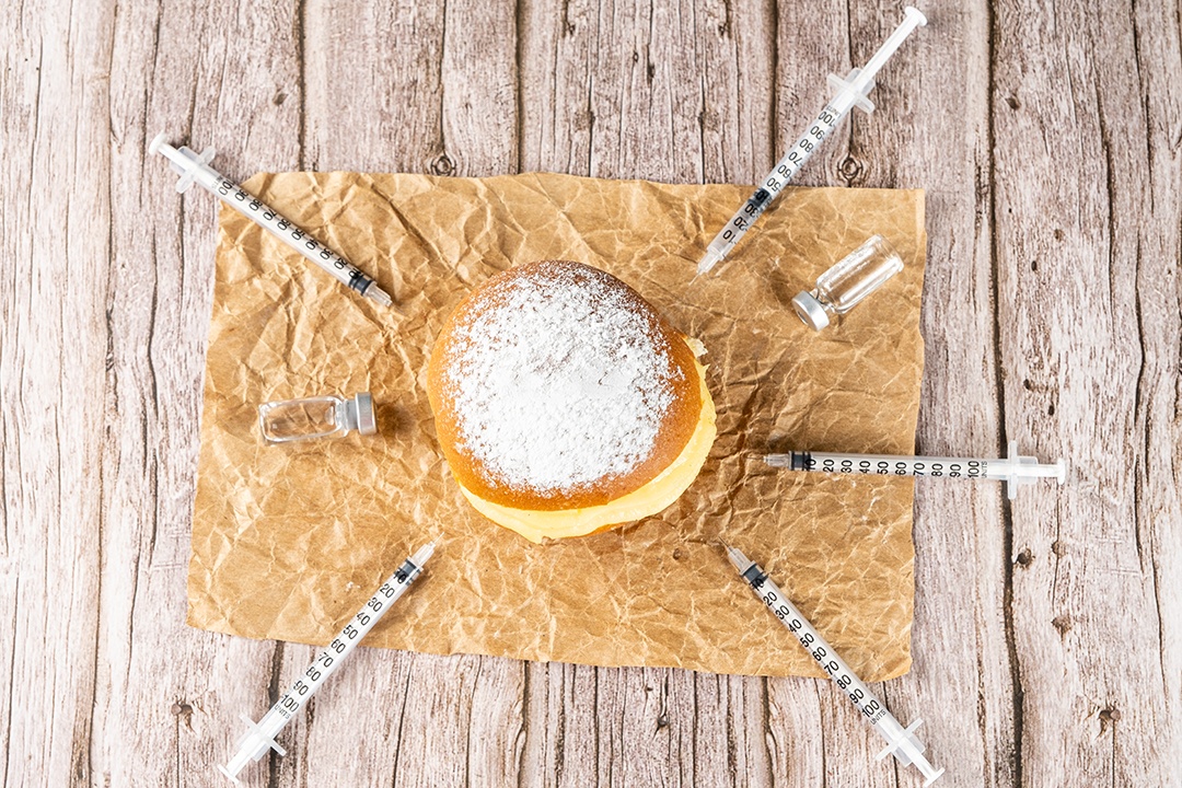 Brazilian cream donuts surrounded by various syringes and ampoules with insulin.