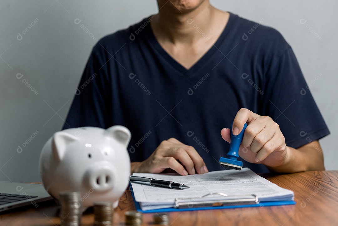 Homem carimbando a aprovação de documentos bancários de finanças de trabalho ou de marketing de investimento na mesa.