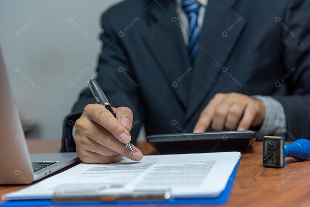 Mão segurando a caneta escrevendo papelada documento de negócios investimento financeiro ou trabalho de contrato de assinatura e seguro na mesa.