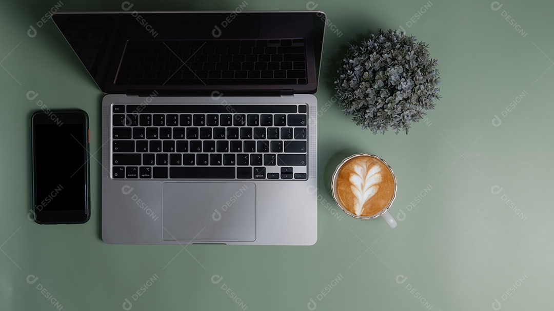 Computador portátil e flor smartphone xícara de café sobre fundo verde.