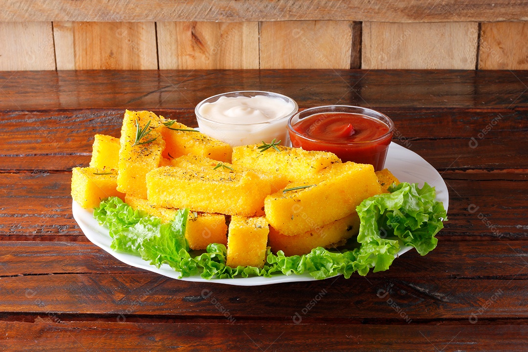 Varas de polenta fritas em placa cerâmica branca sobre de madeira rústica