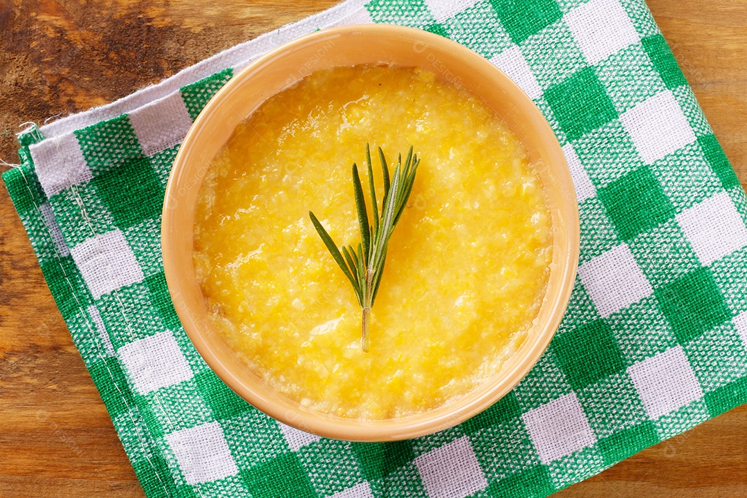 Polenta em tigela de cerâmica na mesa de madeira rústica. Creme de milho