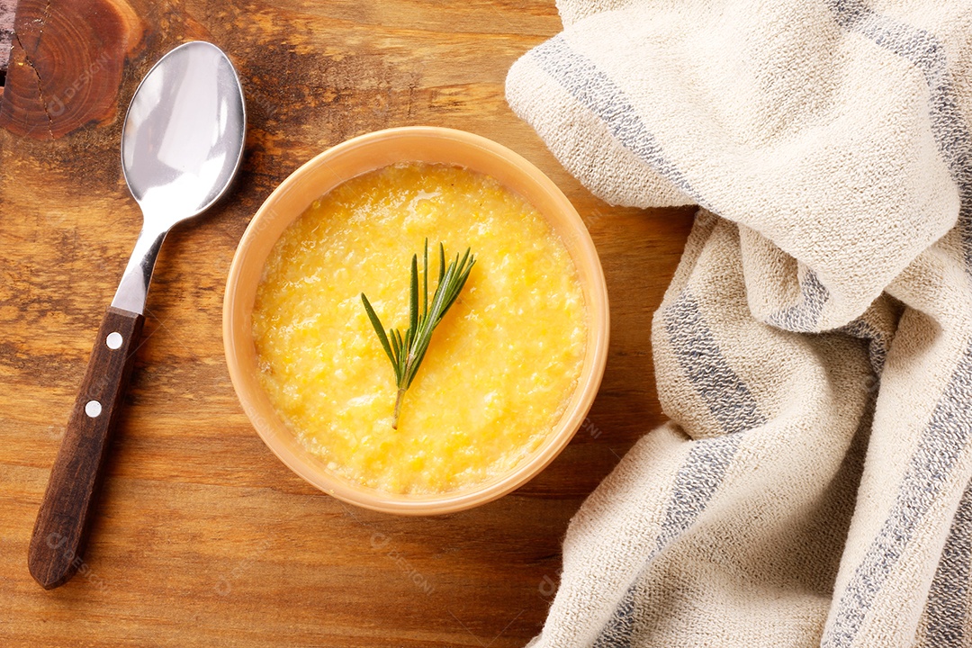 Polenta em tigela de cerâmica na mesa de madeira rústica. Creme de milho