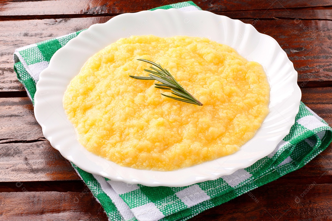 Polenta em prato branco na mesa de madeira rústica. Creme de milho