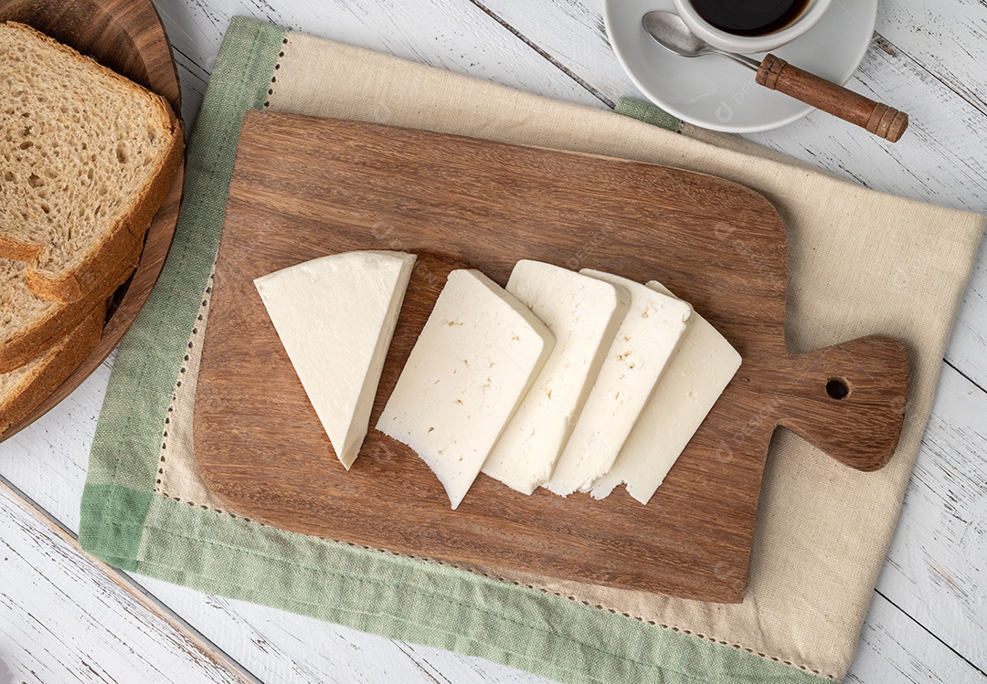 Queijo fresco artesanal de Canastra com café e pão sobre tábua de madeira.