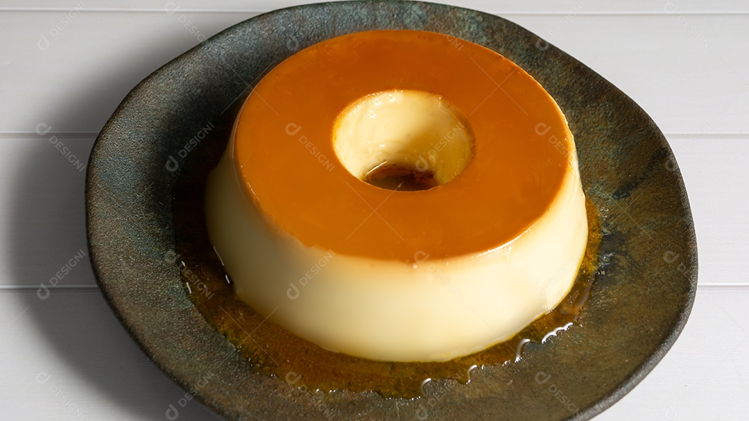 Brazilian flan or flan traditional dessert or known as pudding, top view close-up on the table, dark plate on the table