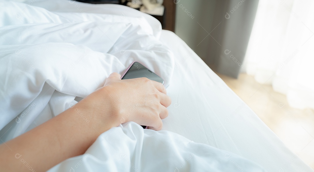 Mulher dormindo na cama e mão segurando o celular.