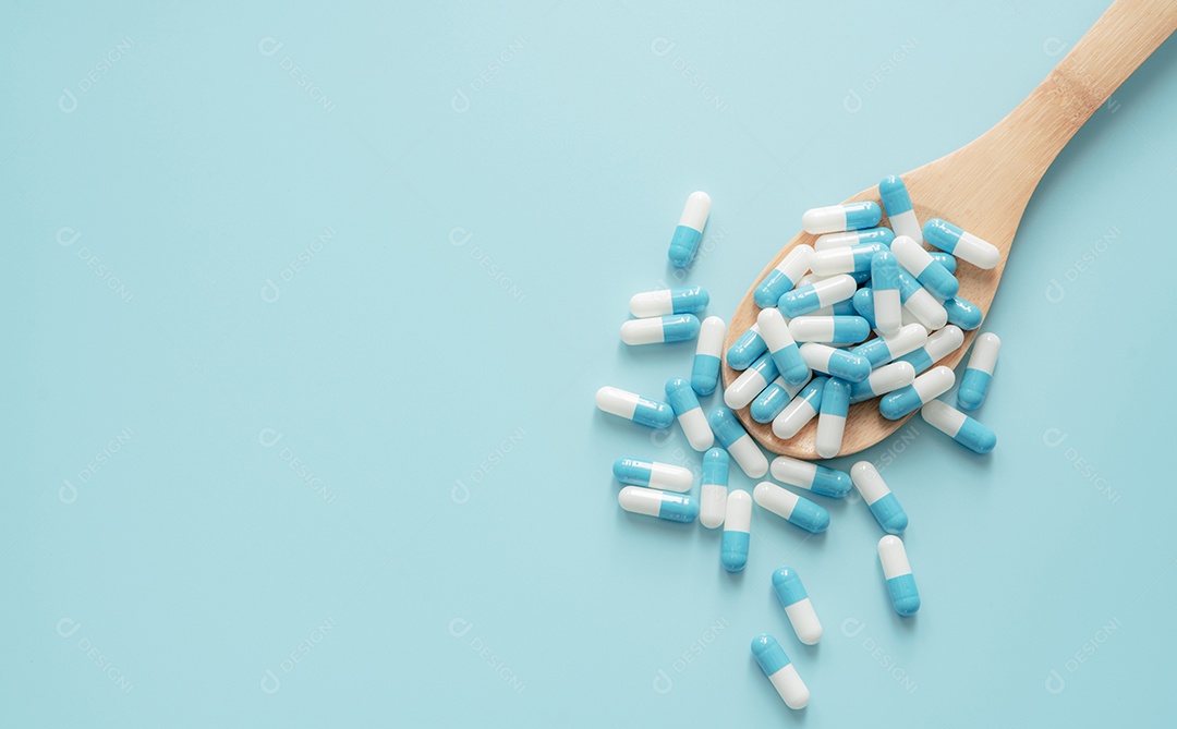 Vista superior de comprimidos de cápsulas de antibióticos azul-branco na colher de pau