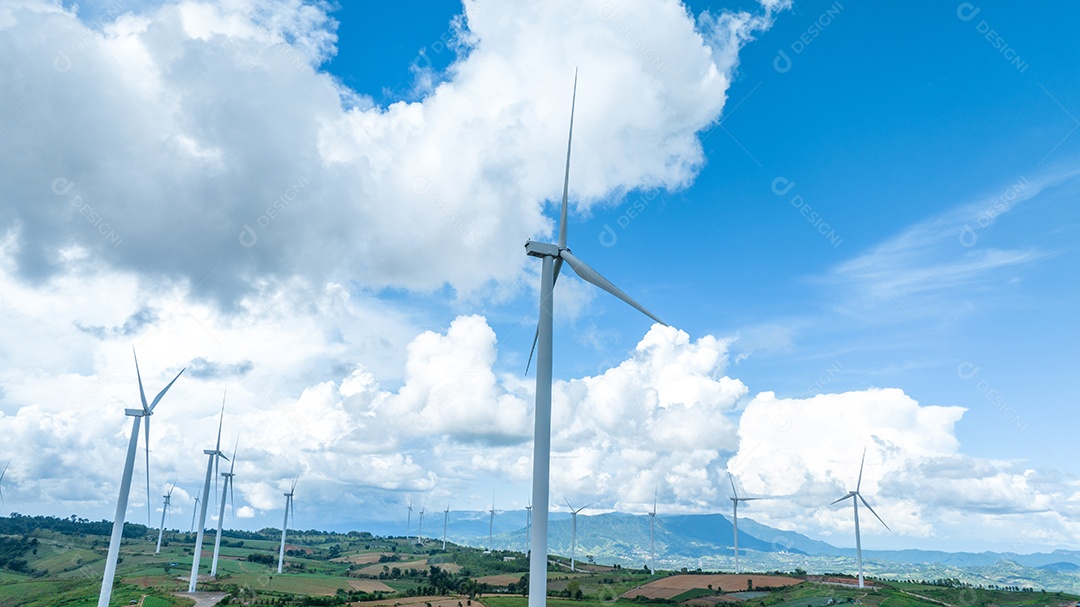 Turbina eólica com céu azul e fundo nublado.