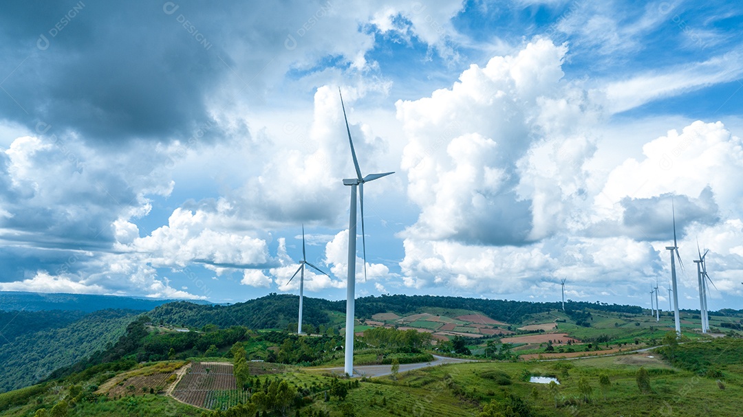 Turbina eólica com céu azul e fundo nublado.