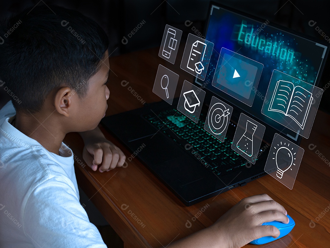 Feche o menino sentado olhando para o laptop e sua mão está segurando mouse.