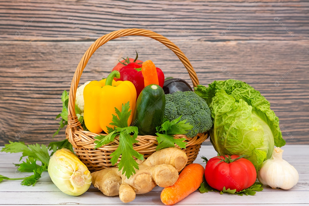 Grupo saudável de vegetais frescos variados em uma cesta de madeira, com vitaminas c de salada, tomate, cenoura