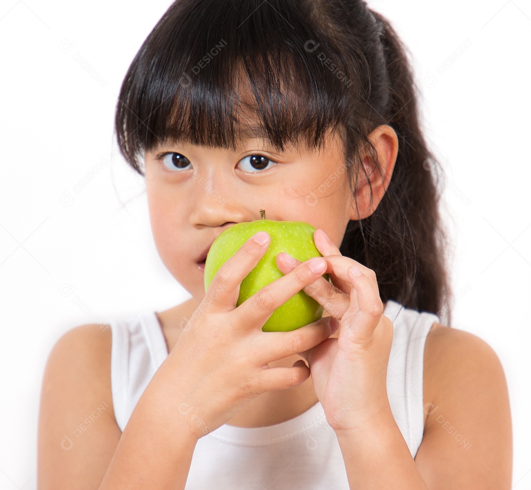 A imagem de uma menina asiática comendo uma maçã verde na mão é saudável e boa para um fundo branco.