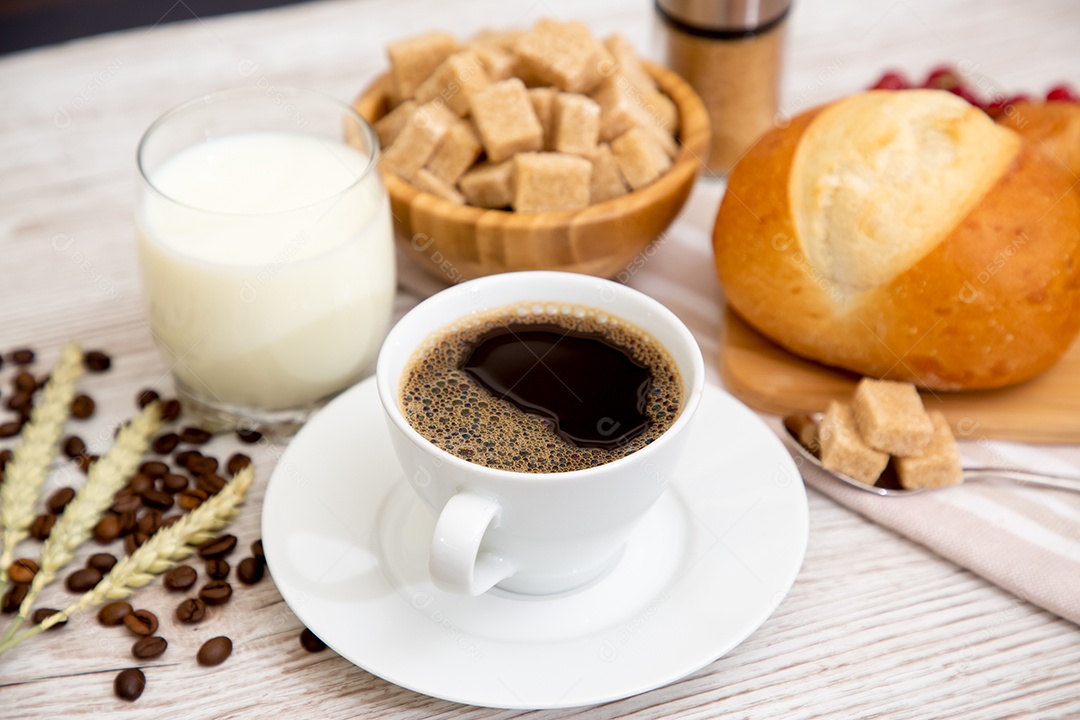 Café da manhã com uma xícara de café preto com pão com croissant e frutas na mesa de madeira.
