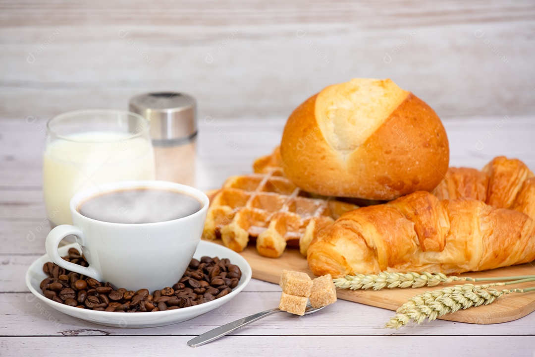 Café da manhã com uma xícara de café preto com pão com croissant e frutas na mesa de madeira.