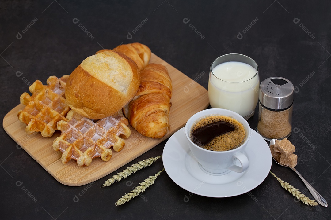 Café da manhã com uma xícara de café preto com pão com croissant e frutas na mesa de madeira.