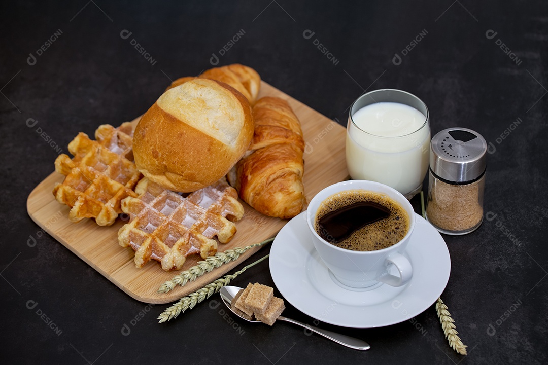 Café da manhã com uma xícara de café preto com pão com croissant e frutas na mesa de madeira.