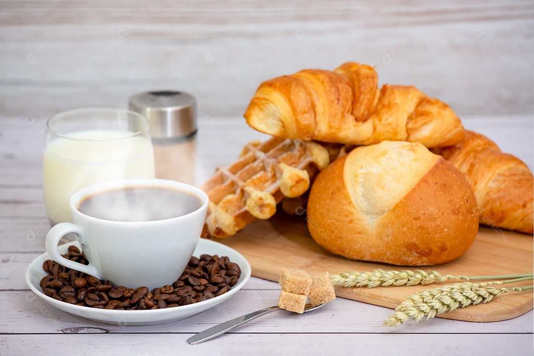 Café da manhã com uma xícara de café preto com pão com croissant e frutas na mesa de madeira.