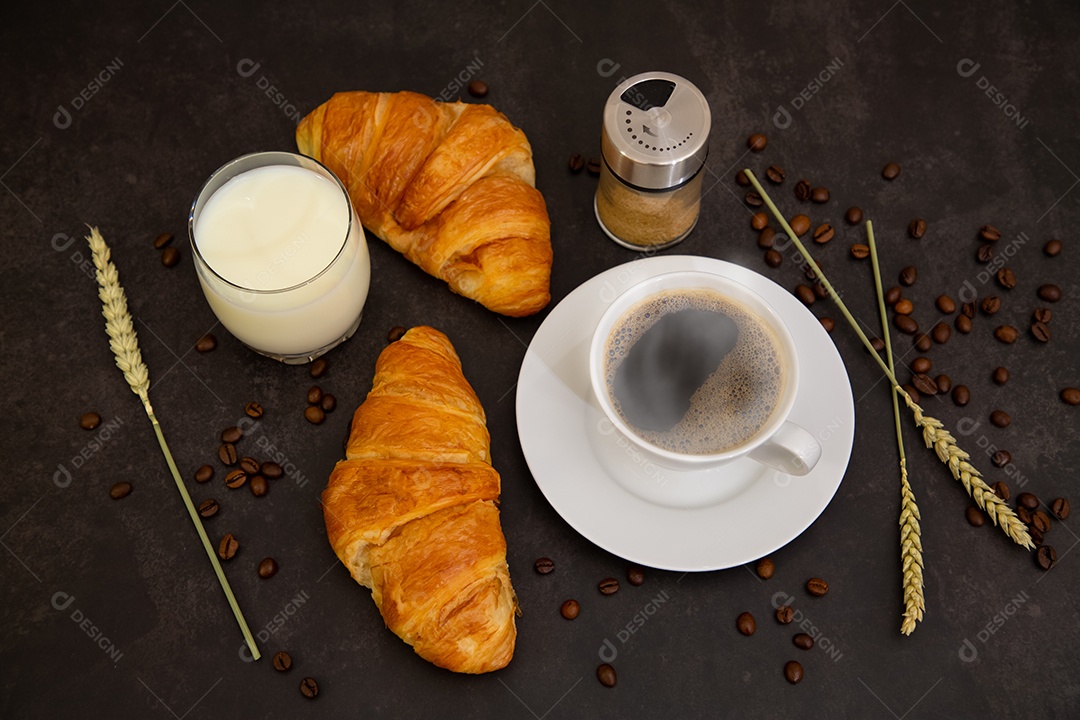 Café da manhã com uma xícara de café preto com pão com croissant e frutas na mesa de madeira.