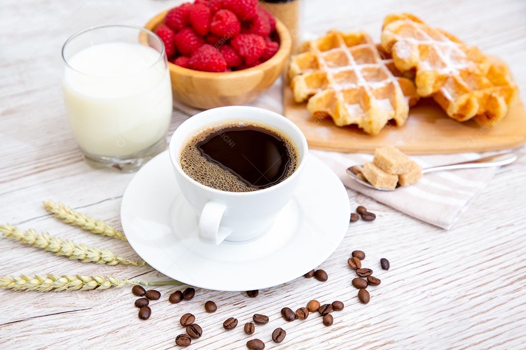 Café da manhã com uma xícara de café preto com pão com croissant e frutas na mesa de madeira.