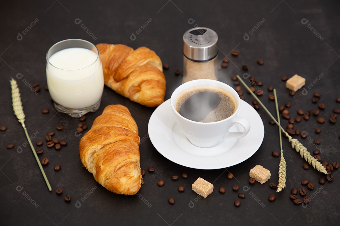 Café da manhã com uma xícara de café preto com pão com croissant e frutas na mesa de madeira.
