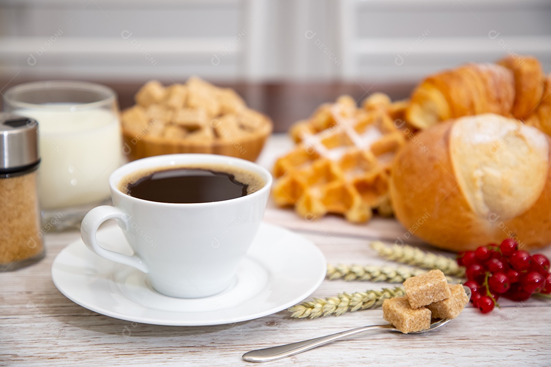 Café da manhã com uma xícara de café preto com pão com croissant e frutas na mesa de madeira.