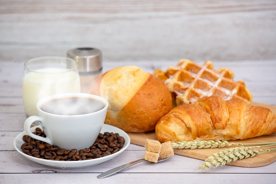 Café da manhã com uma xícara de café preto com pão com croissant e frutas na mesa de madeira.