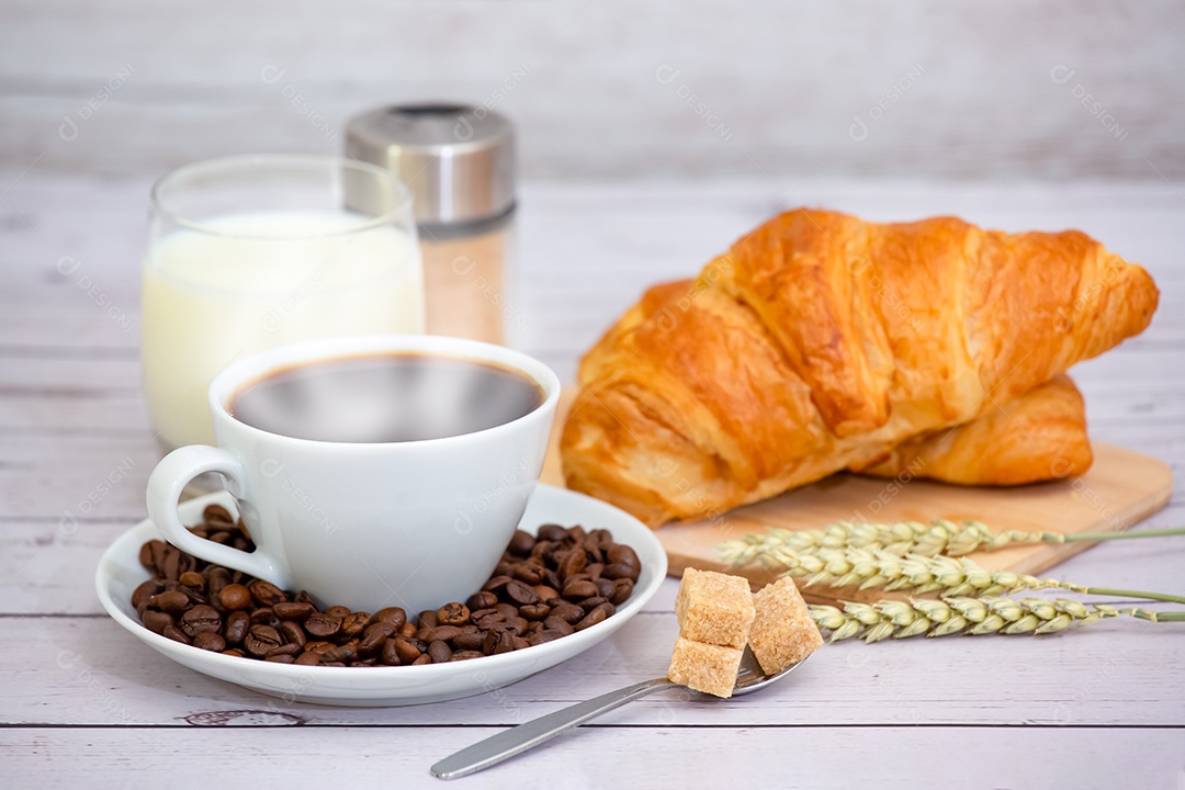 Café da manhã com uma xícara de café preto com pão com croissant e frutas na mesa de madeira.