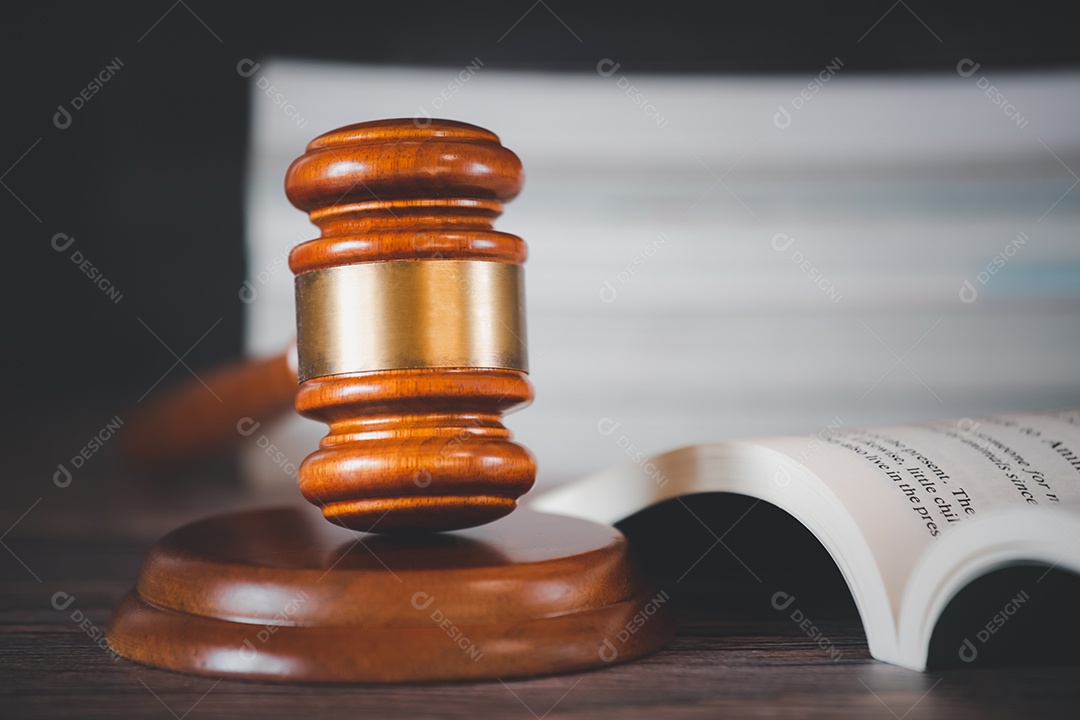 Martelo de juiz de madeira velho com livro de direito sobre o fundo de madeira da mesa, usado para julgamento e justiça.