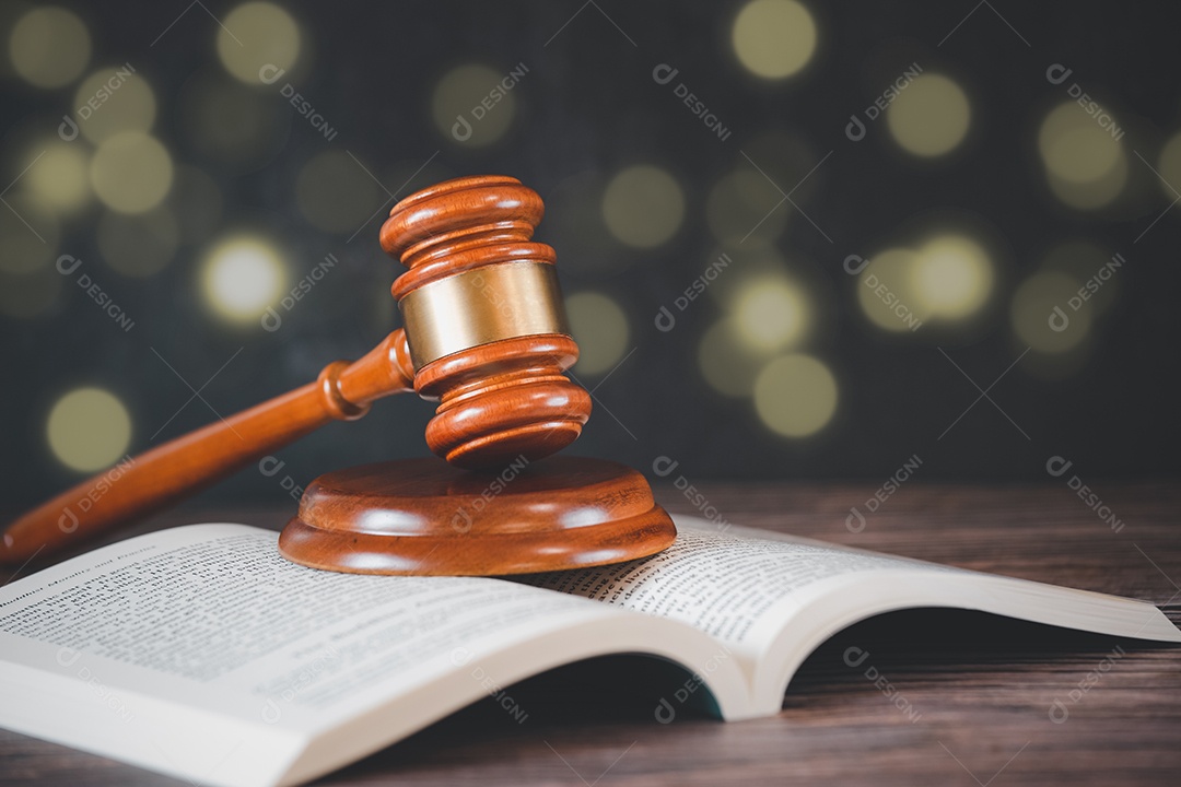 Martelo de juiz de madeira velho com livro de direito sobre o fundo de madeira da mesa, usado para julgamento e justiça.