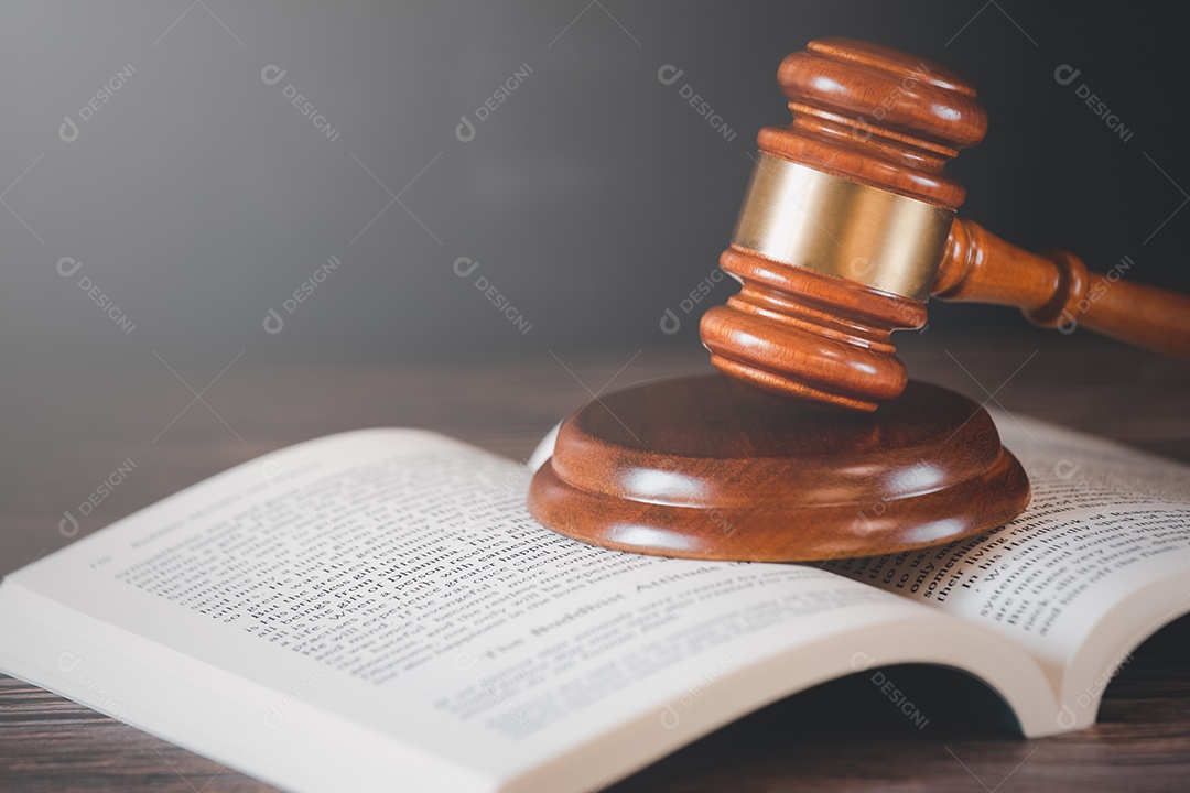Martelo de juiz de madeira velho com livro de direito sobre o fundo de madeira da mesa, usado para julgamento e justiça.