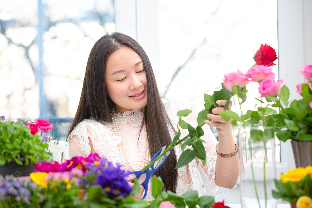 Mulher se preparando para aparar rosas vermelhas e cor de rosa e lindos arranjos de flores em casa