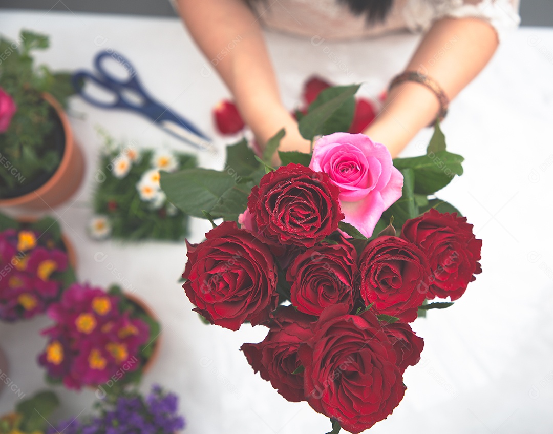 Mulher se preparando para aparar rosas vermelhas e cor de rosa e lindos arranjos de flores em casa