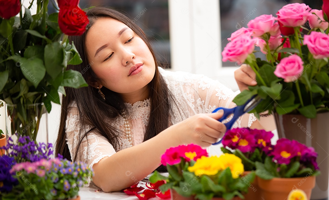 Mulher se preparando para aparar rosas vermelhas e cor de rosa e lindos arranjos de flores em casa
