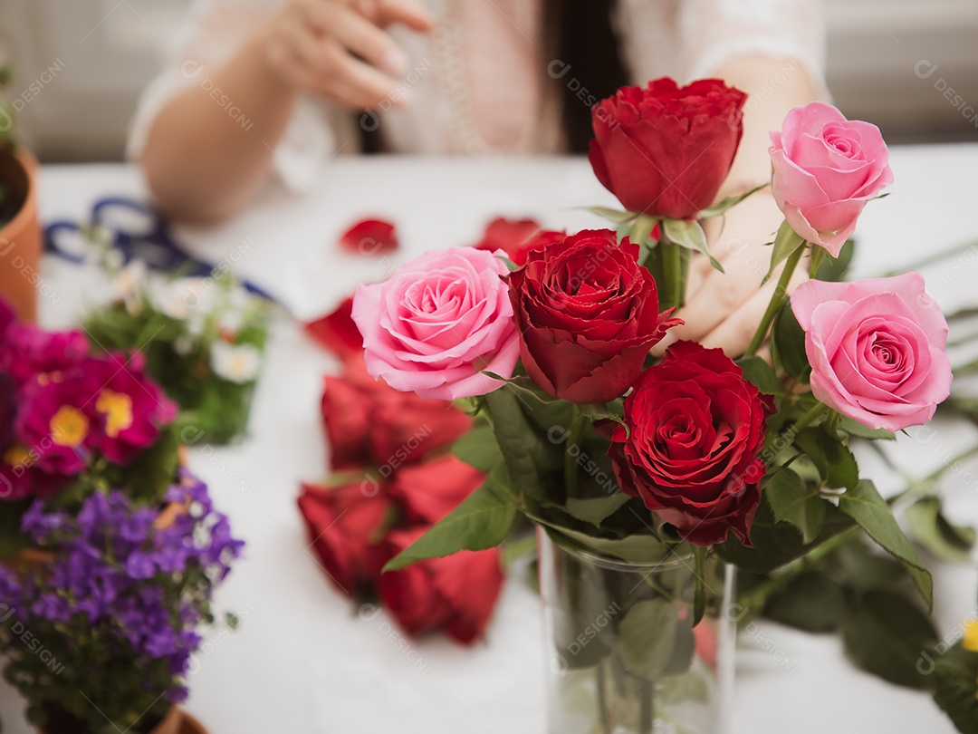 Mulher se preparando para aparar rosas vermelhas e cor de rosa e lindos arranjos de flores em casa