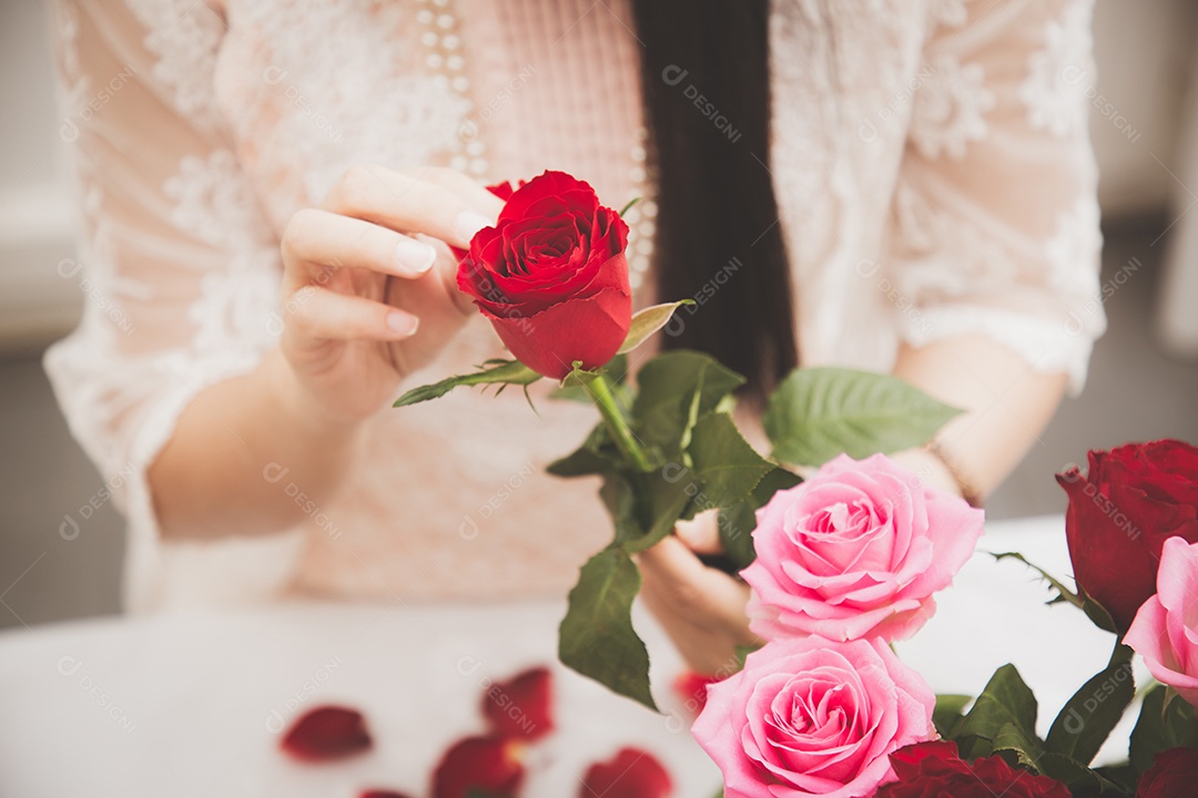 Mulher se preparando para aparar rosas vermelhas e cor de rosa e lindos arranjos de flores em casa