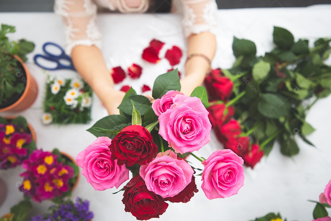 Mulher se preparando para aparar rosas vermelhas e cor de rosa e lindos arranjos de flores em casa