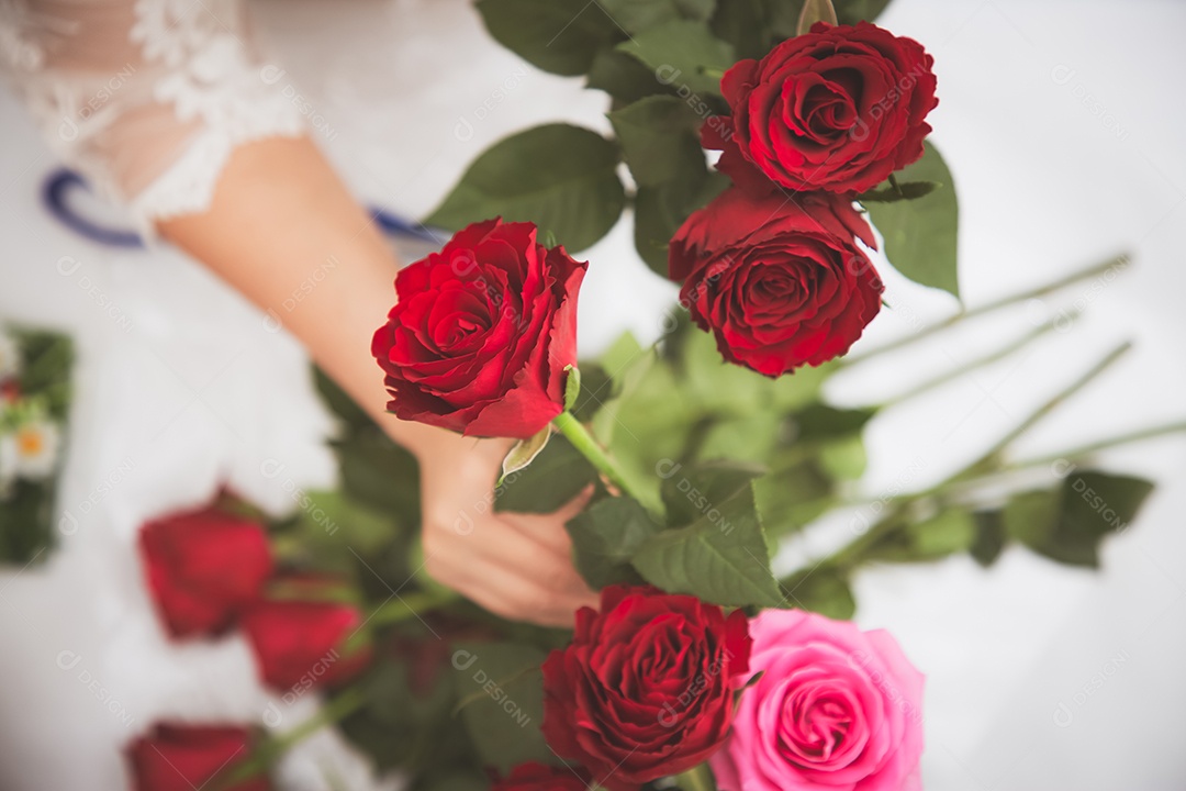 Mulher se preparando para aparar rosas vermelhas e cor de rosa e lindos arranjos de flores em casa