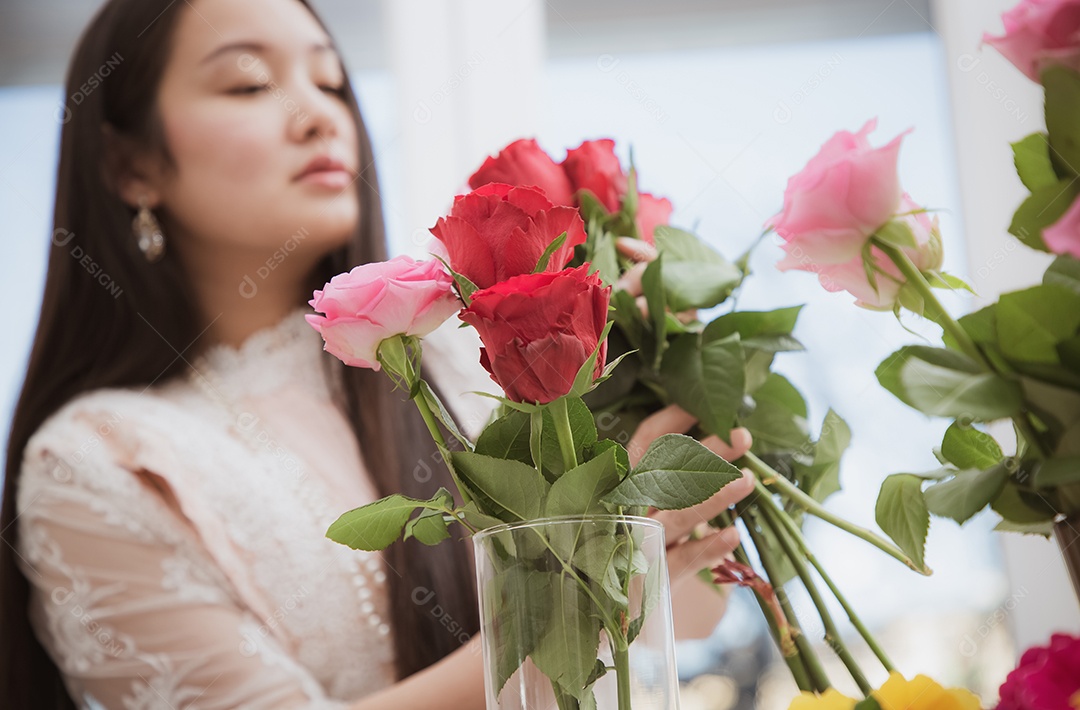 Mulher se preparando para aparar rosas vermelhas e cor de rosa e lindos arranjos de flores em casa