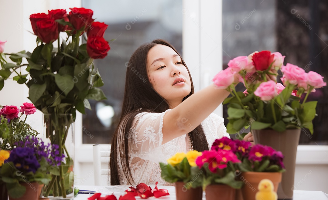 Mulher se preparando para aparar rosas vermelhas e cor de rosa e lindos arranjos de flores em casa
