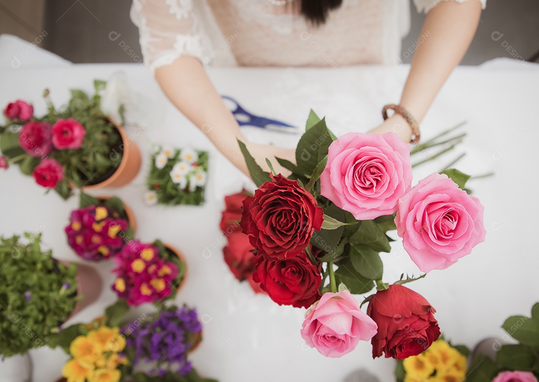 Mulher se preparando para aparar rosas vermelhas e cor de rosa e lindos arranjos de flores em casa