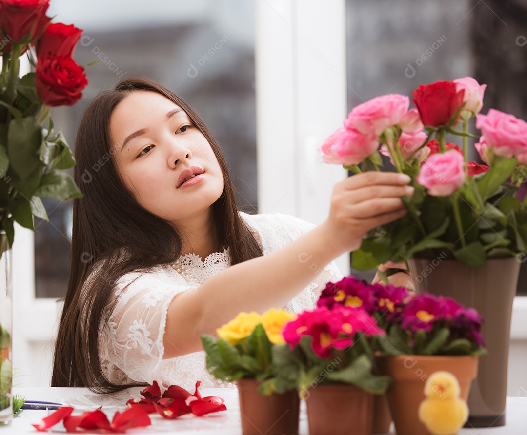 Mulher se preparando para aparar rosas vermelhas e cor de rosa e lindos arranjos de flores em casa