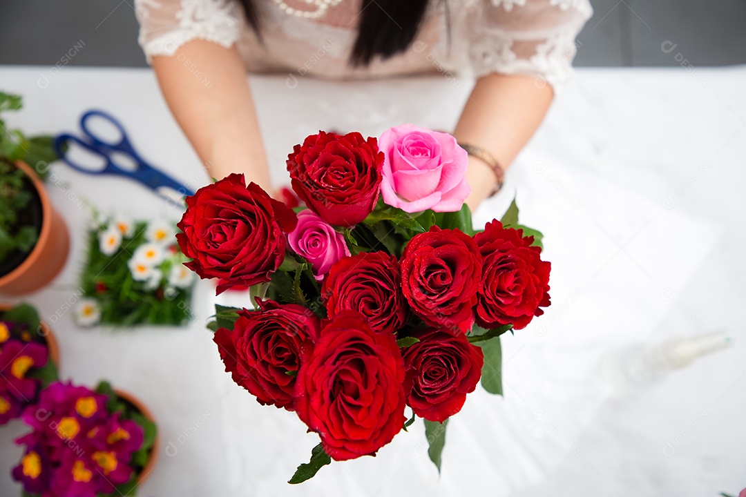 Mulher se preparando para aparar rosas vermelhas e cor de rosa e lindos arranjos de flores em casa