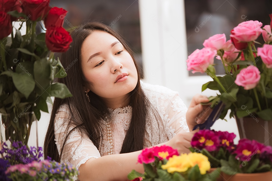Mulher se preparando para aparar rosas vermelhas e cor de rosa e lindos arranjos de flores em casa