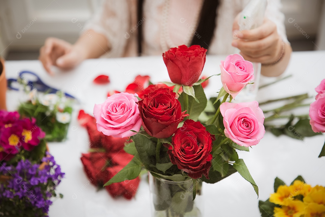 Mulher se preparando para aparar rosas vermelhas e cor de rosa e lindos arranjos de flores em casa