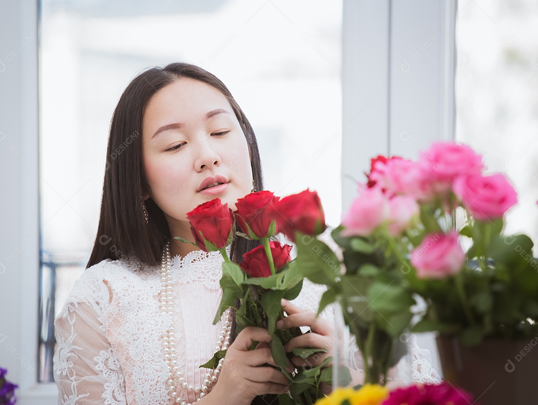 Mulher se preparando para aparar rosas vermelhas e cor de rosa e lindos arranjos de flores em casa
