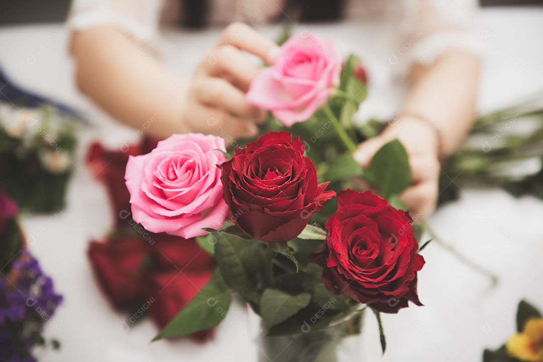 Mulher se preparando para aparar rosas vermelhas e cor de rosa e lindos arranjos de flores em casa