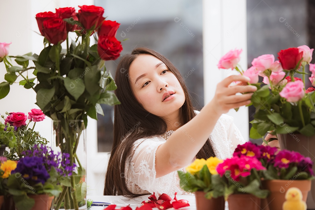 Mulher se preparando para aparar rosas vermelhas e cor de rosa e lindos arranjos de flores em casa