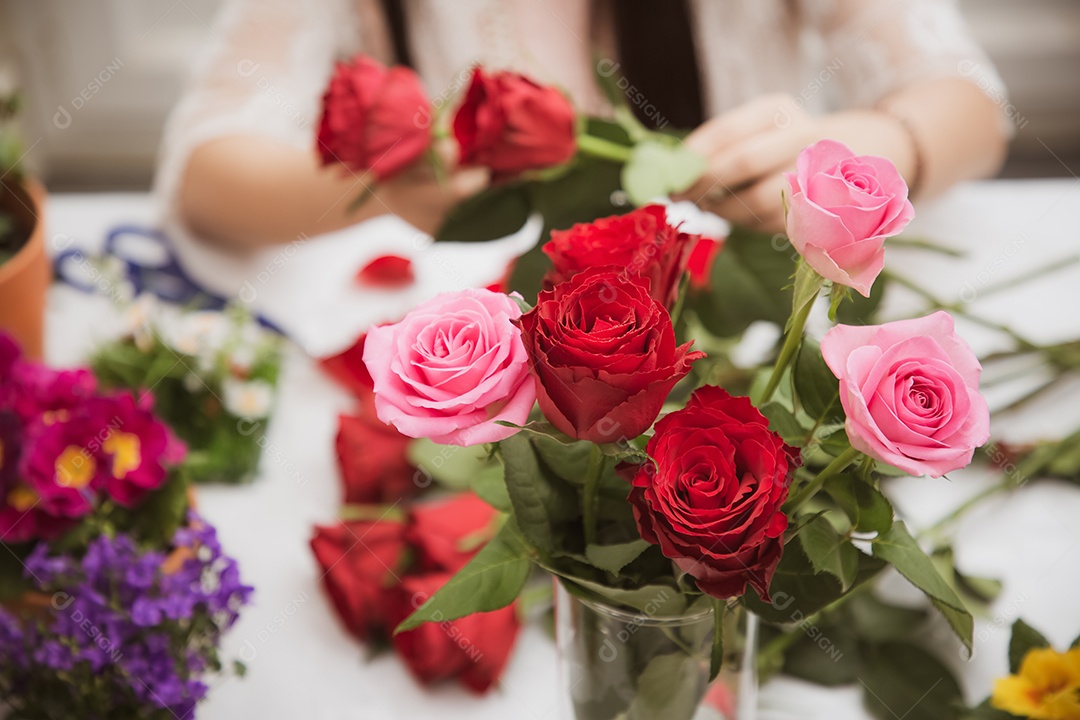 Mulher se preparando para aparar rosas vermelhas e cor de rosa e lindos arranjos de flores em casa