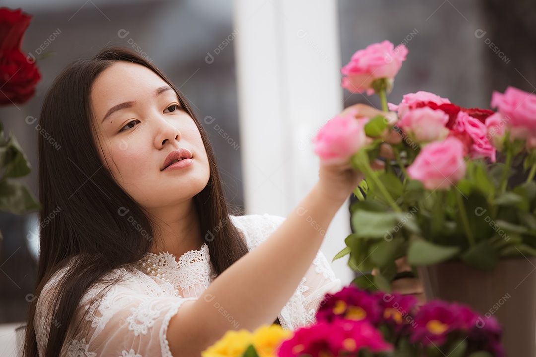 Mulher se preparando para aparar rosas vermelhas e cor de rosa e lindos arranjos de flores em casa